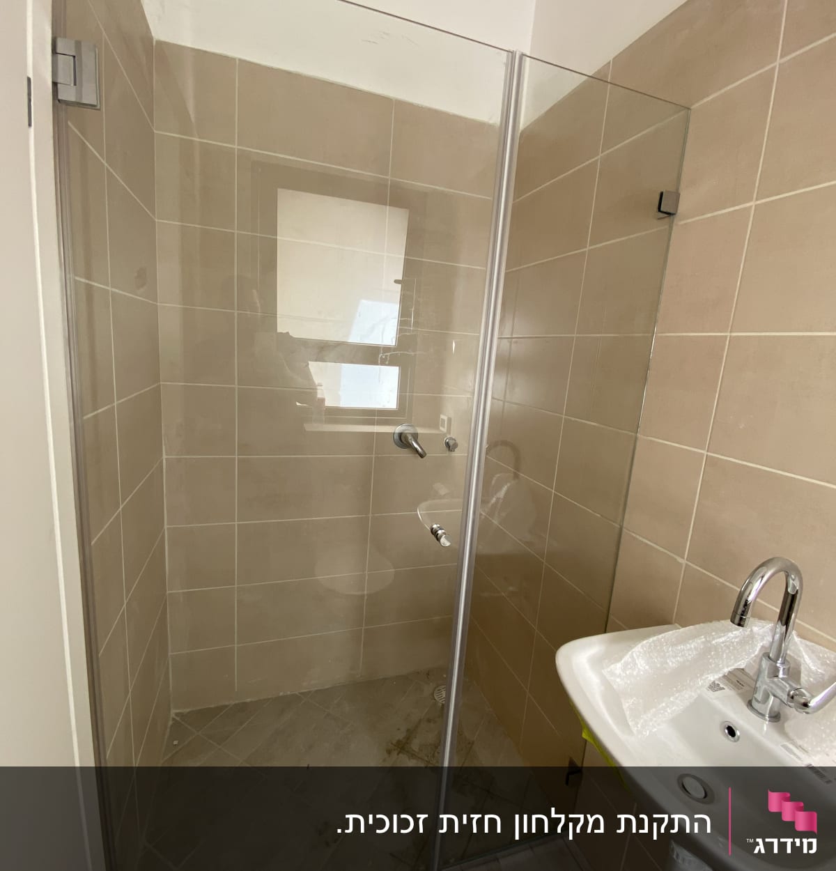 מקלחון זכוכית עם קירות אריחים חומים וברז מתכת